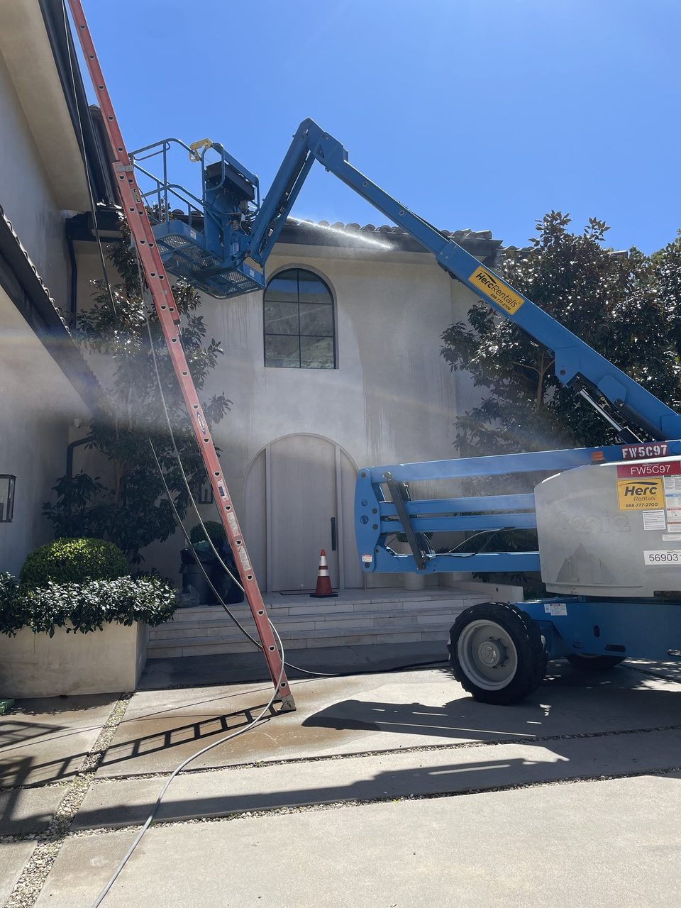 Gorilla Exterior Cleaning technician on a boom lift pressure washing the upper exterior of a two-story Los Angeles home